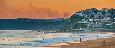 a long distance shot of Newcaste beach as the sun sets