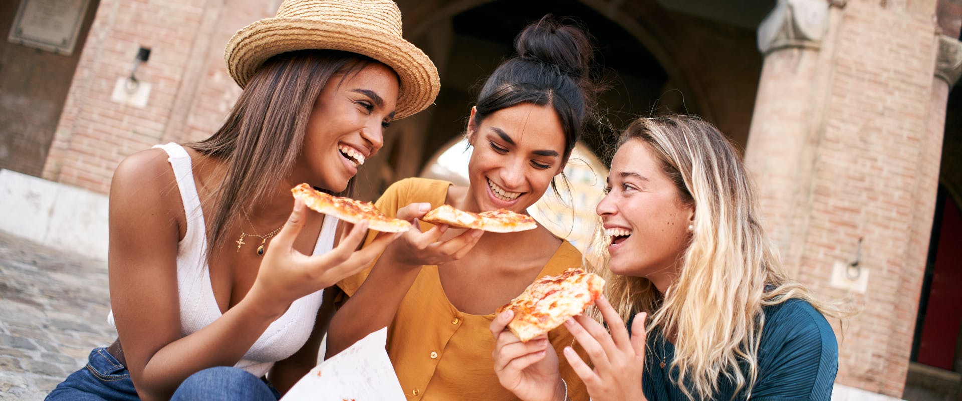 A group of solo female travelers eating pizza in Milan.
