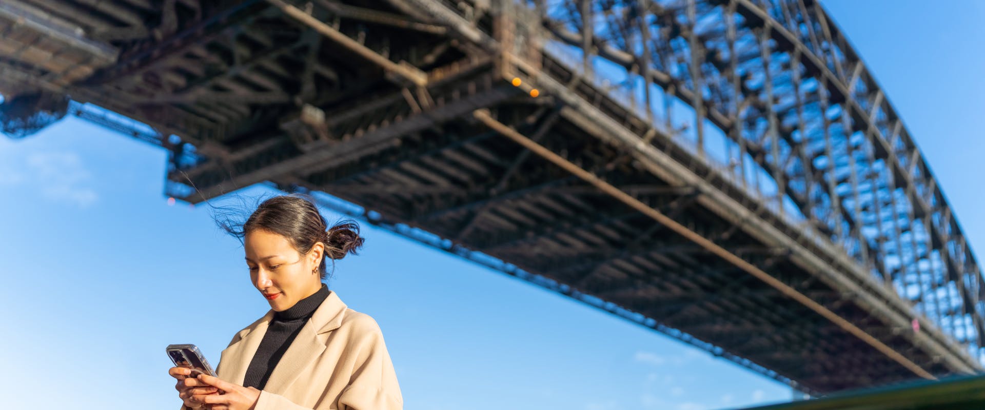 a solo female traveler with her back to sydney harbour bridge