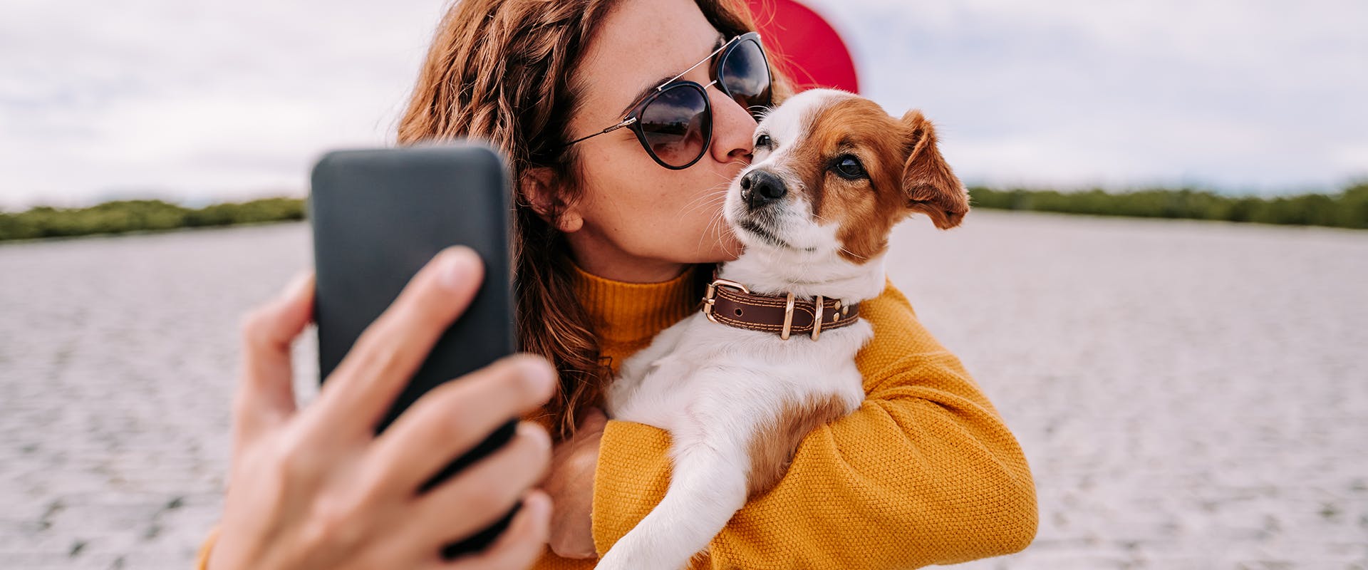 A woman holding a dog in her arms while taking a selfie