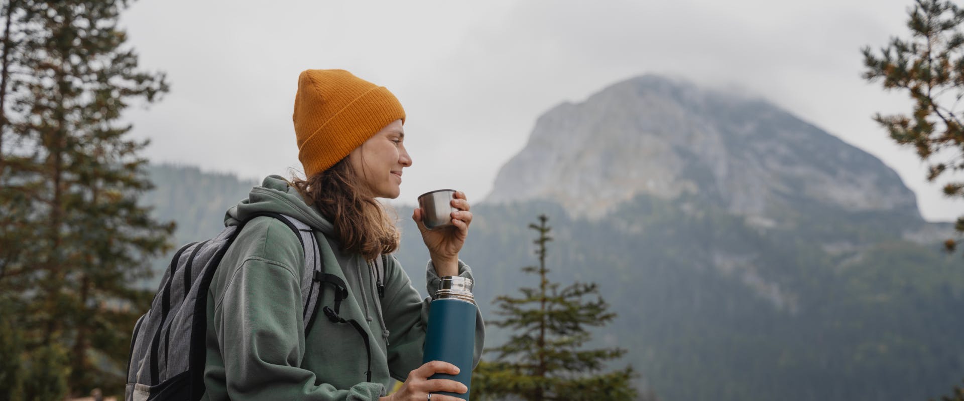 solo female traveler enjoying a warm drink on a solo camping mountain trip