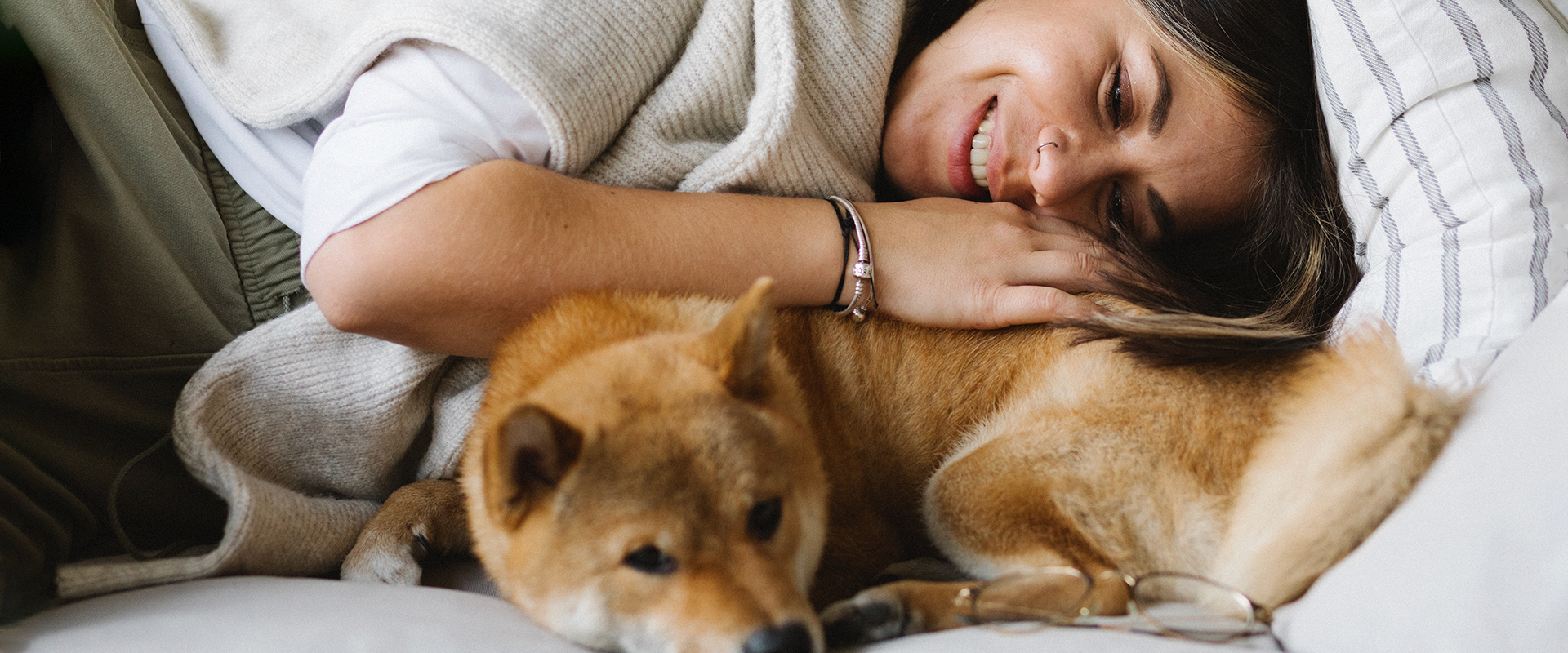 A woman laying on a sofa hugging a dog