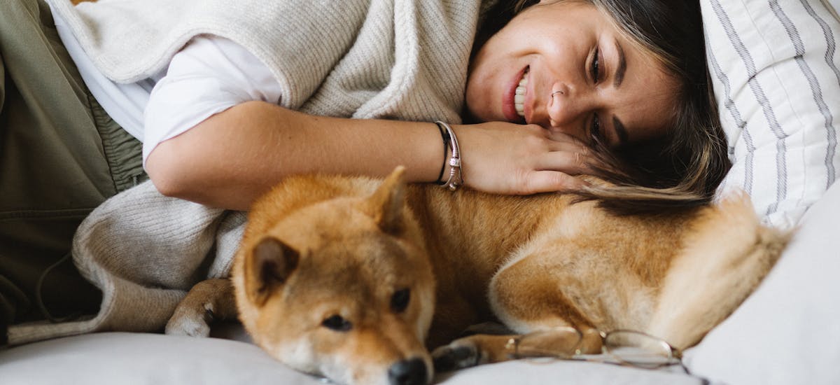 Woman cuddling on the sofa with a Shiba Inu dog
