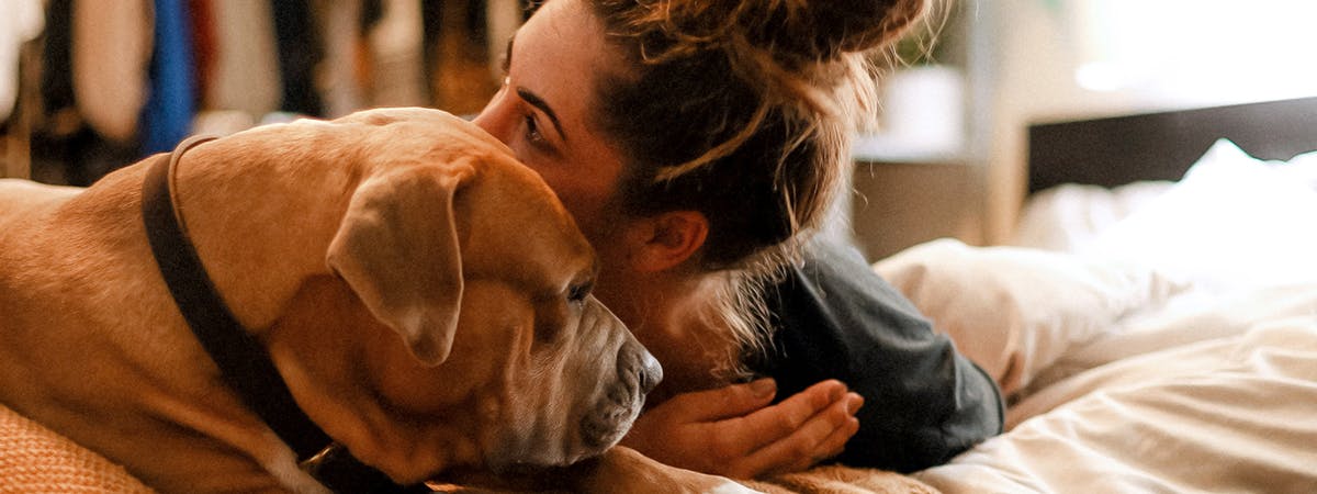 A woman cuddling a brown dog
