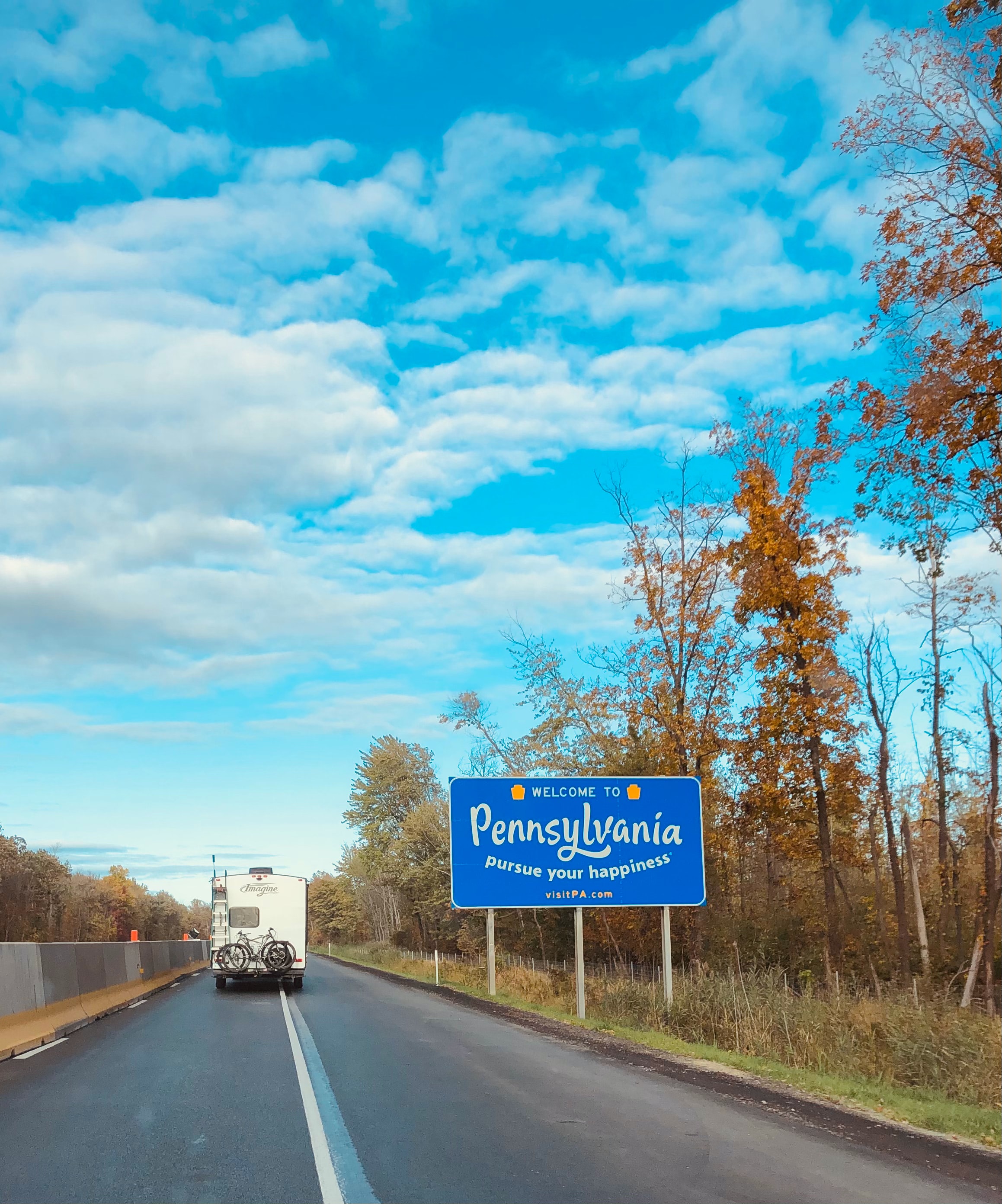 State sign with the text 'Welcome to Pennsylvania, pursue your happiness' written on it