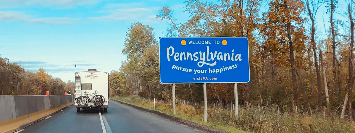 State sign with the text 'Welcome to Pennsylvania, pursue your happiness' written on it