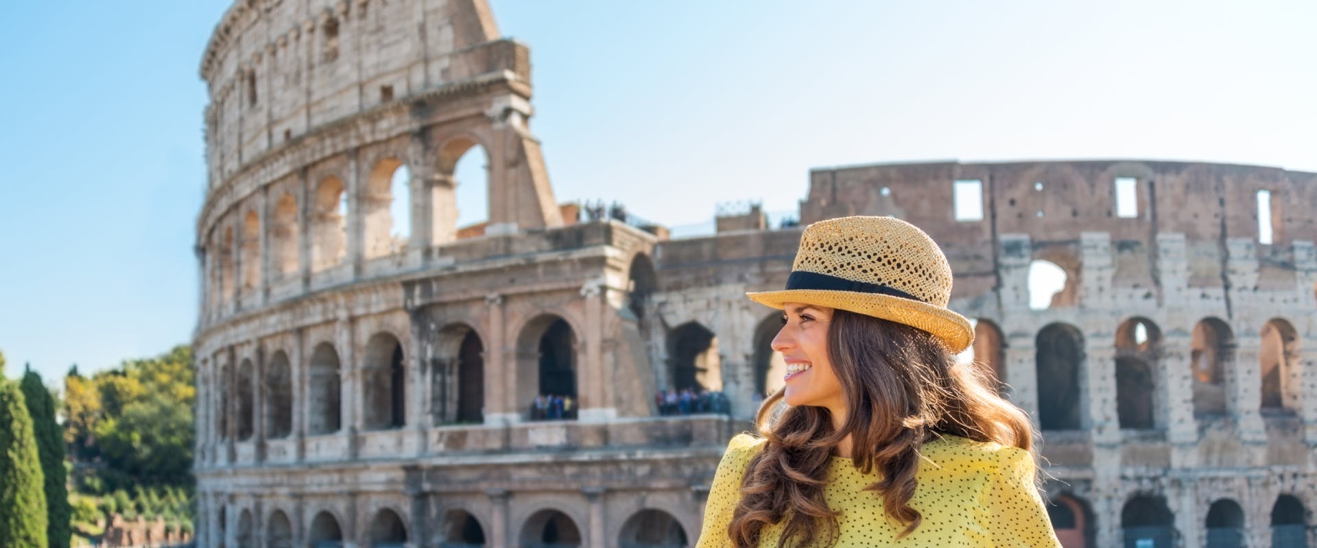 A woman stands in front of the Colosseum 