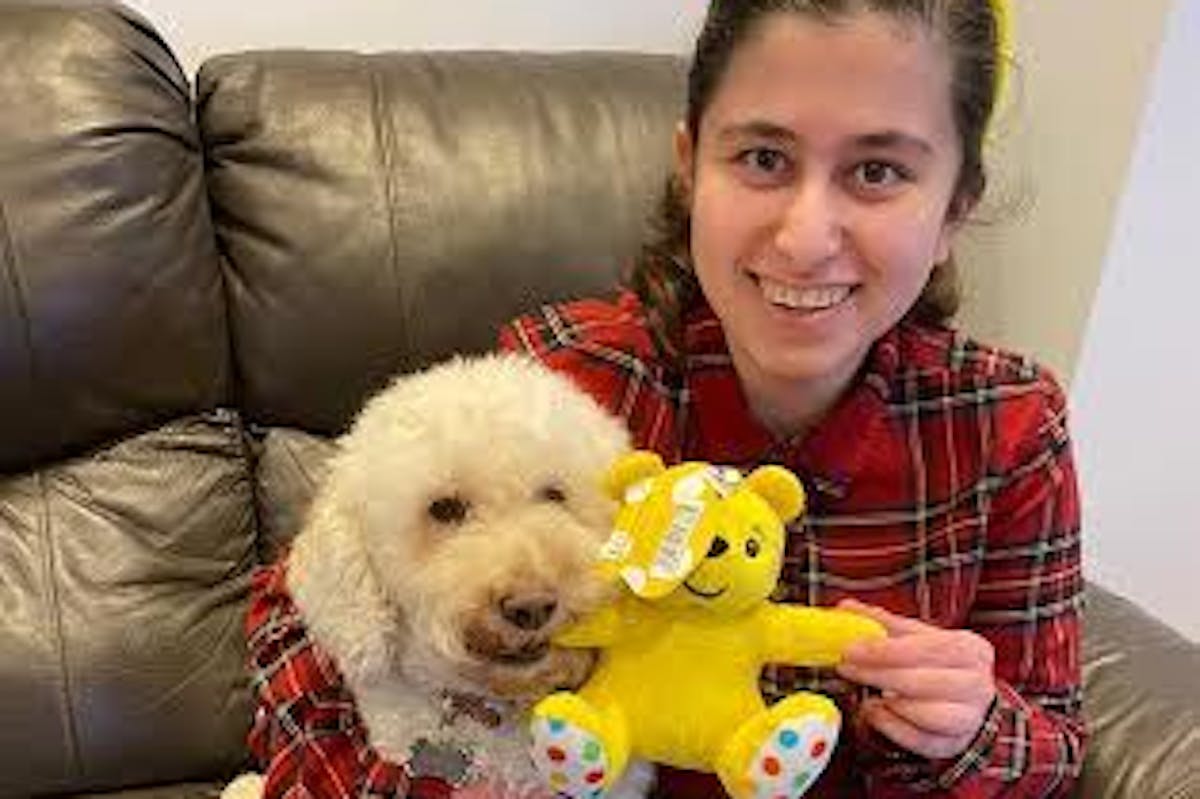 A girl sitting on the sofa holding a dog 