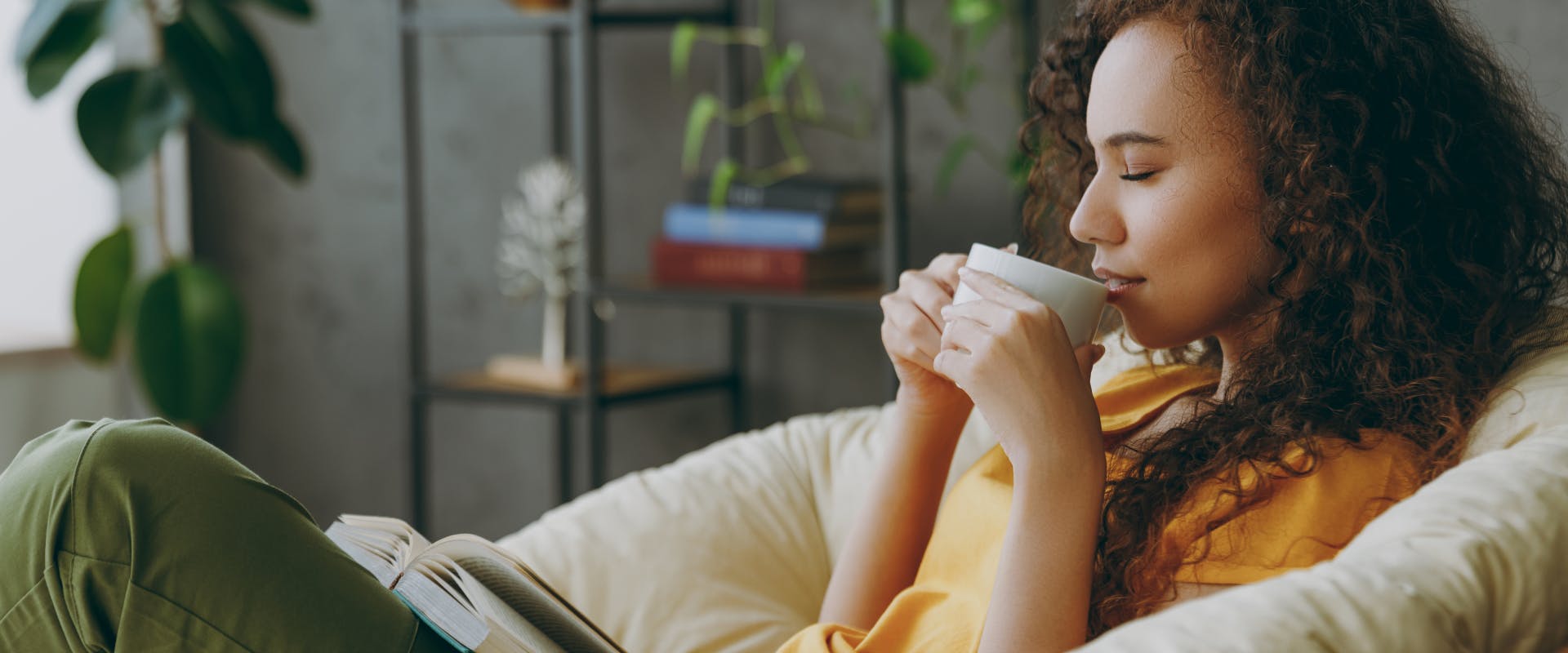 A woman enjoys slowing down with a cup of coffee and a book.
