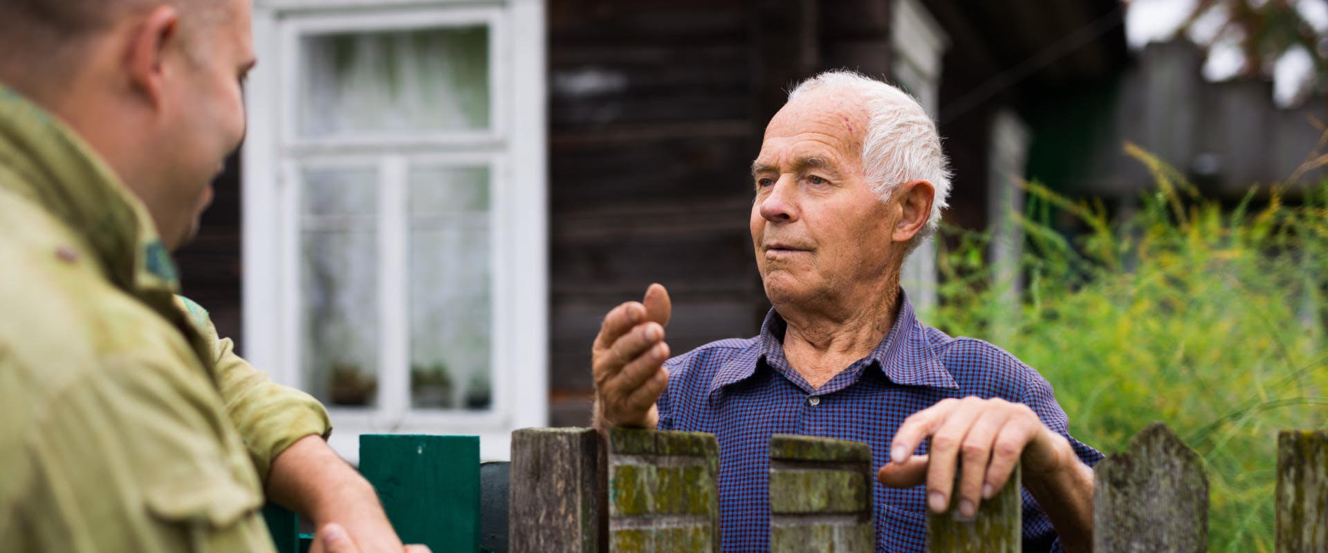 two men talking over a wooden fence who are part of the local rural communities