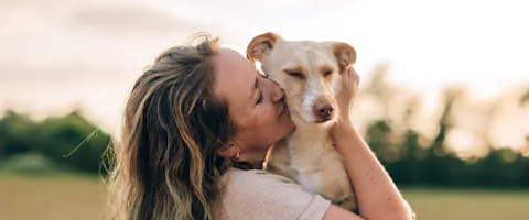 Person embracing a dog in a field