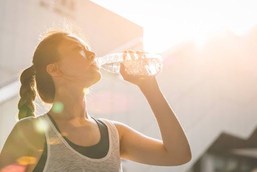 Woman in exercise clothes drinking out of a water bottle.