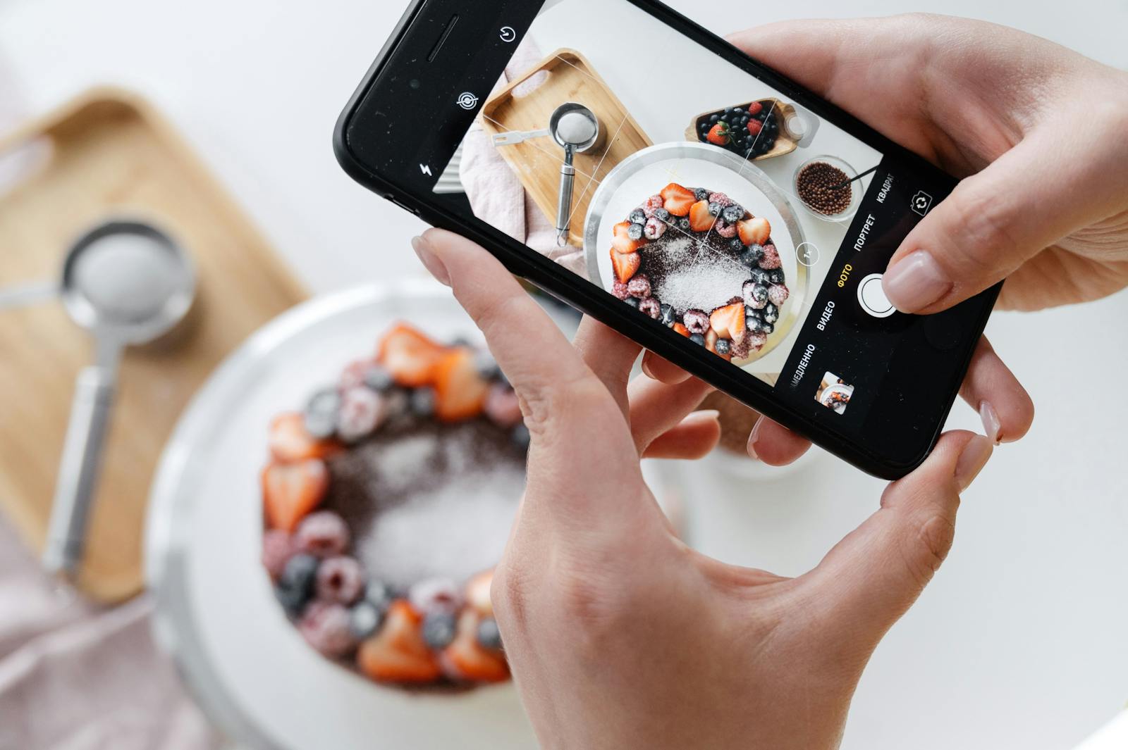 Using an iPhone to take picture of pancake with fruit.