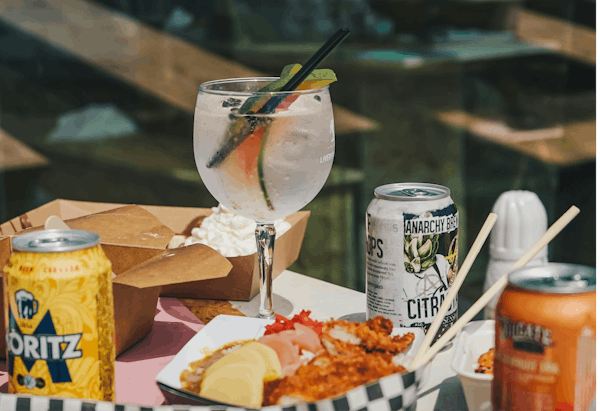 Image of delivered food with a cocktail glass and craft beer cans