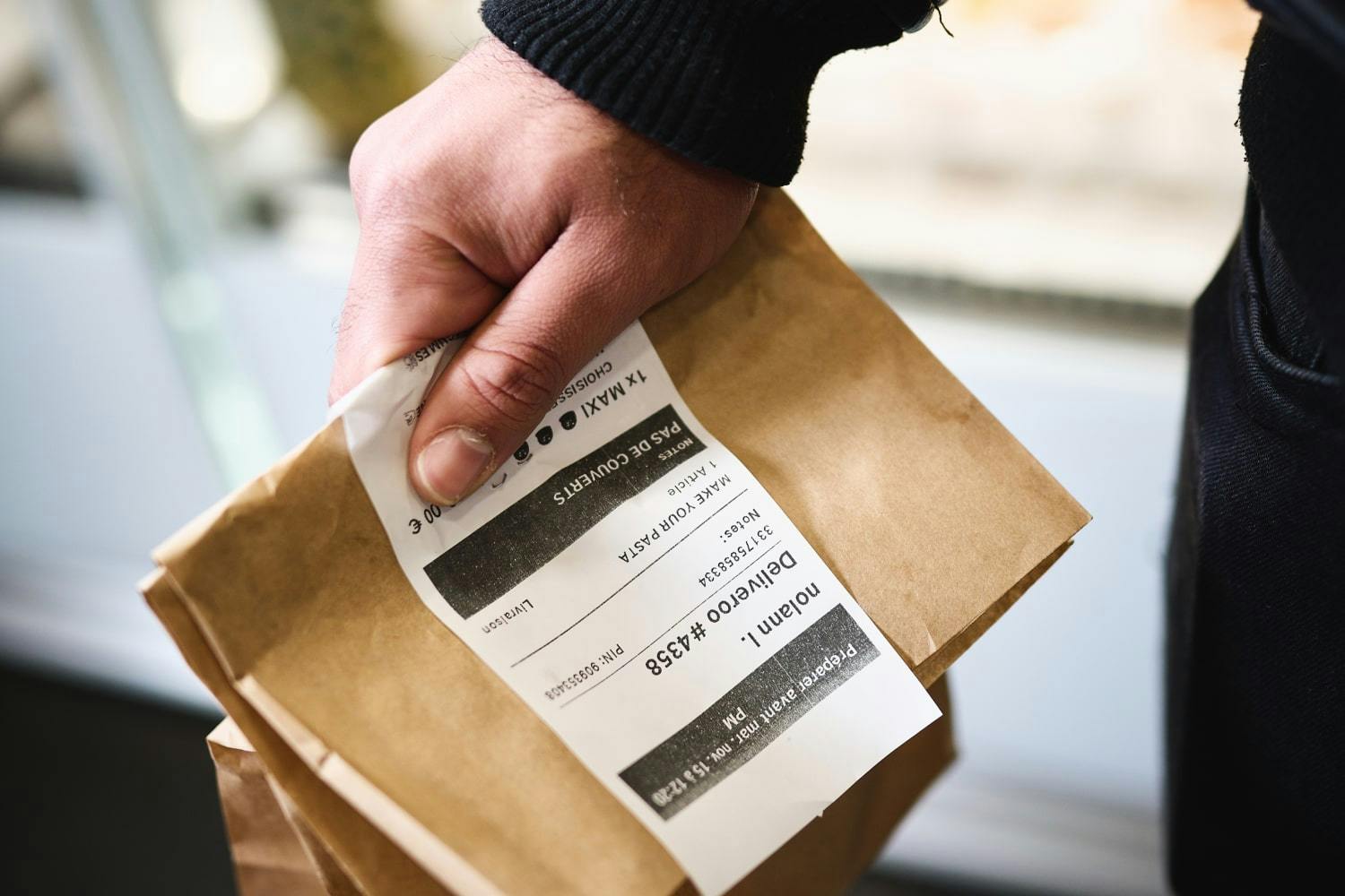 Image of a person holding a food delivery package with the receipt on the top