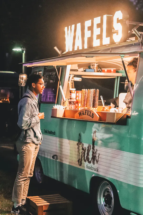 A delivery courier standing outside a food truck. 