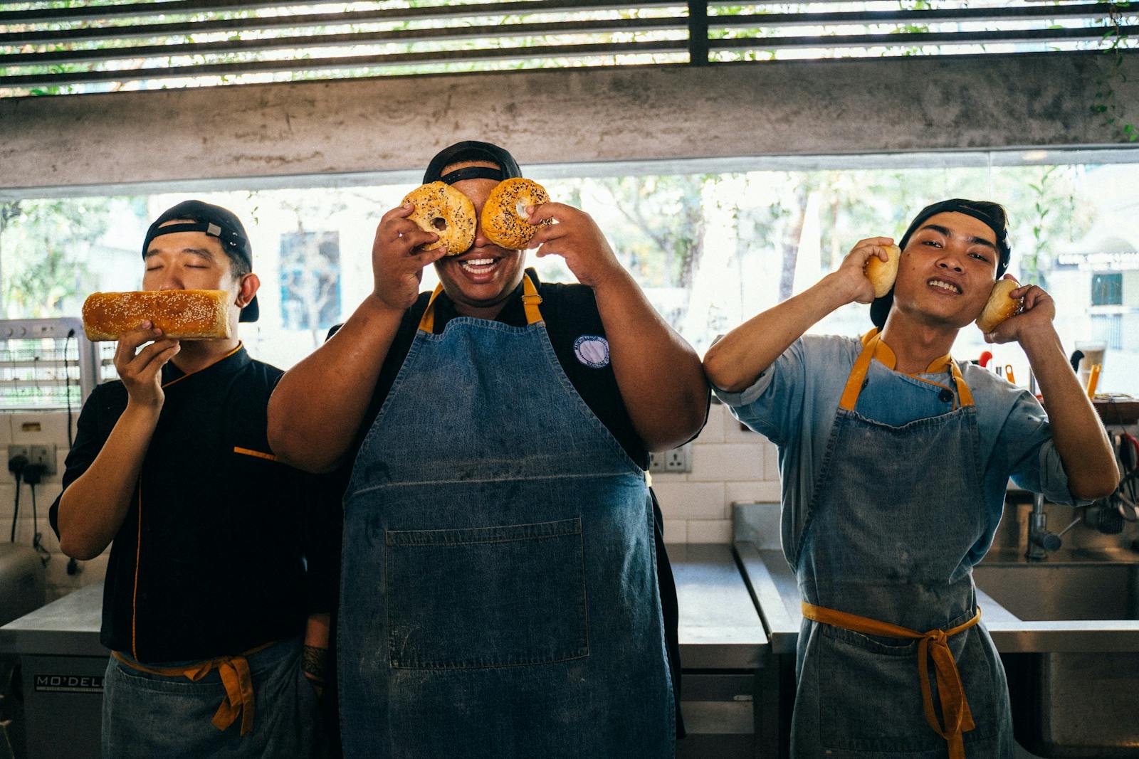 Funny restaurant workers holding up bagels.