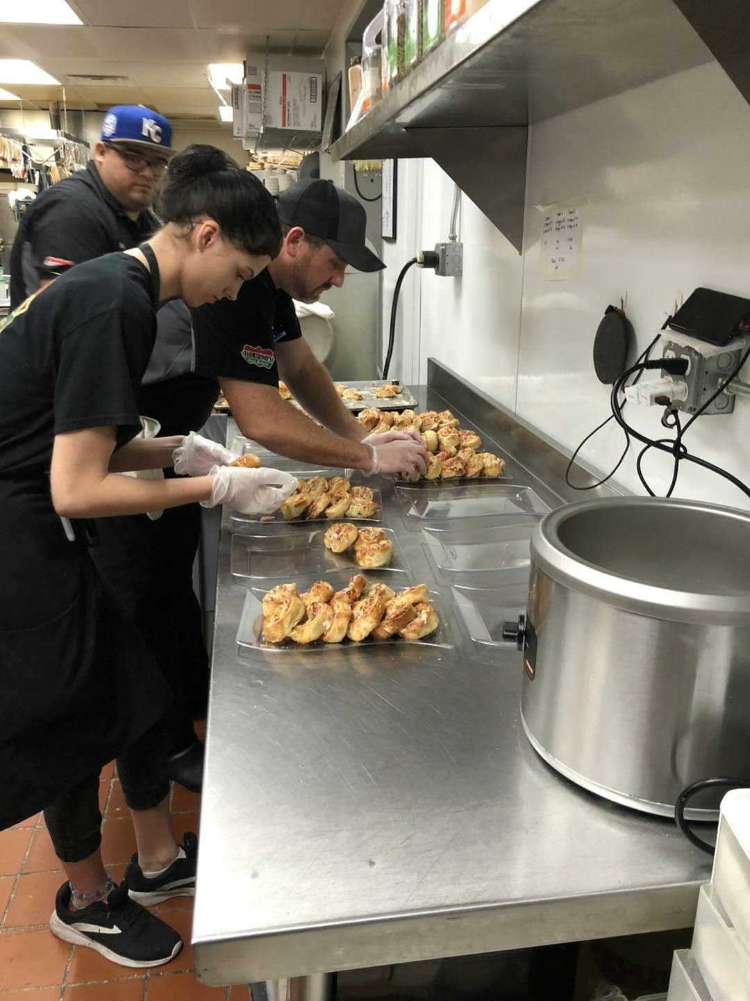 Three Floridino's staff members preparing their pizza muffins