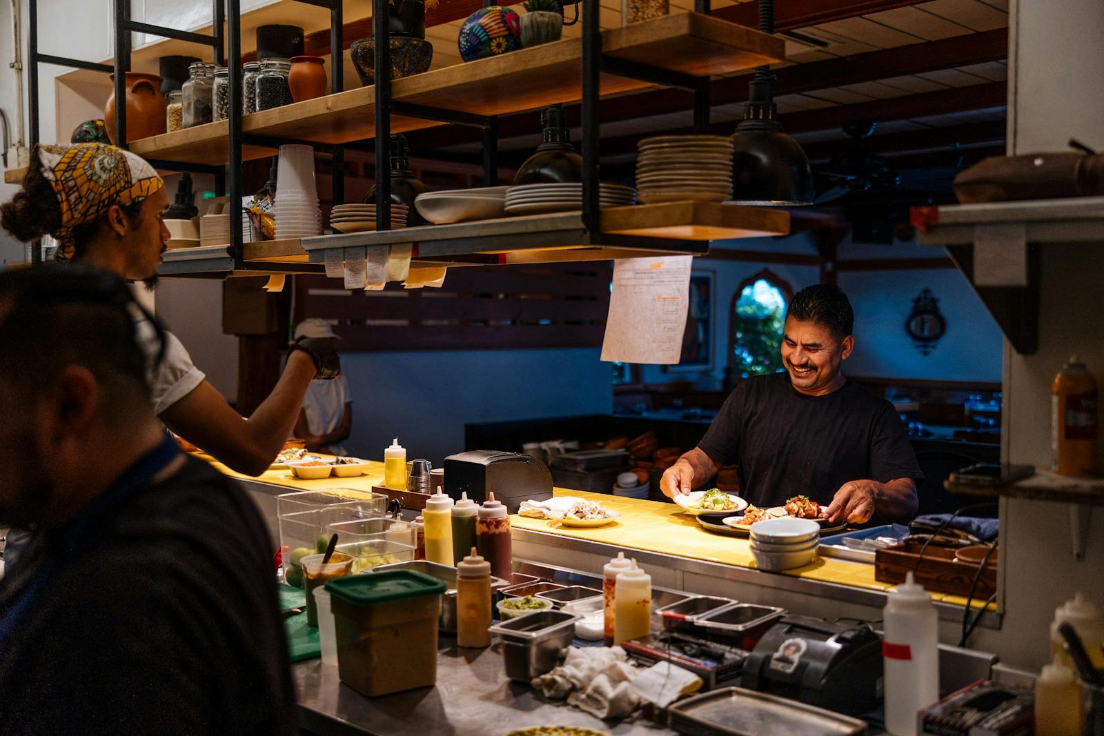 Image of restaurant employee smiling as a he grabs a plate to run it to a table