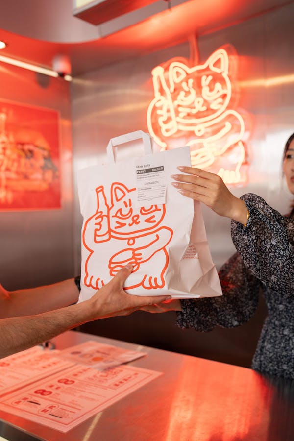 Image of restaurant employee in a trendy restaurant handing a delivery order off to a courier