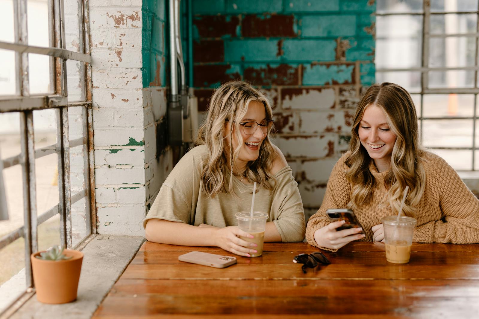 Women using a cell phone at a restaurant.