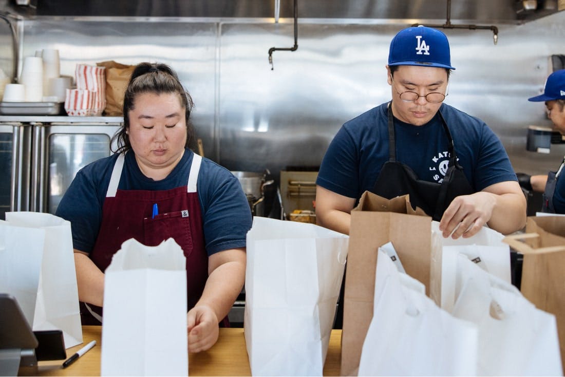 Image of two restaurant workers packing for delivery