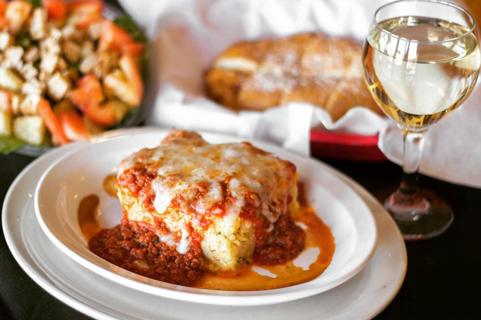 Image of a piece of lasagna and a glass of white wine from Floridino's