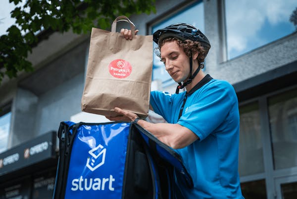 Image of a Stuart delivery partner placing a food package into the delivery bag