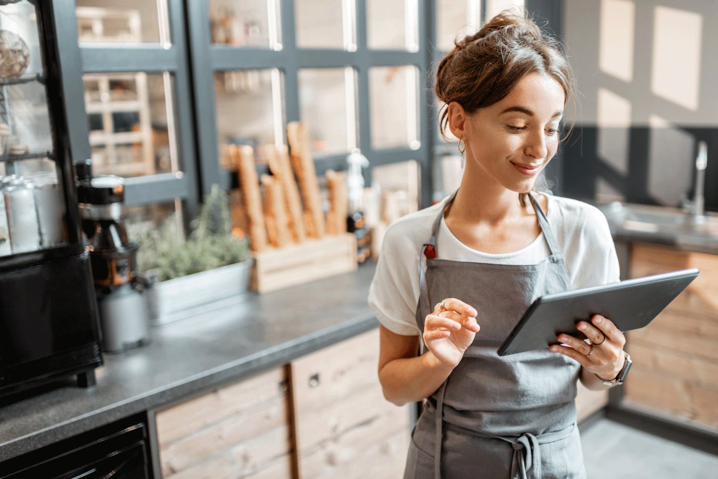 Image of a restaurant staff smiling and looking at the tablet in her hands