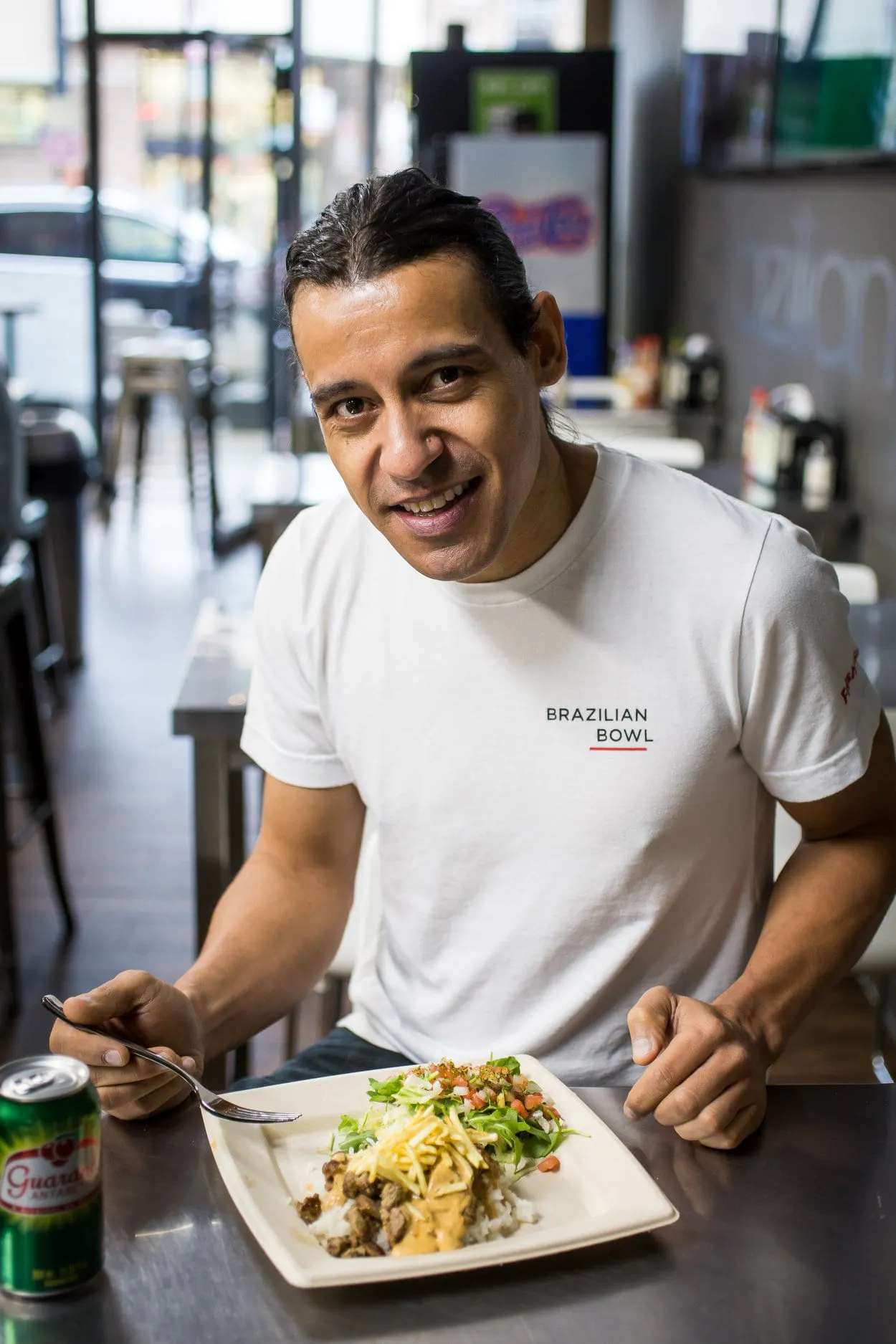 Image of Tony Ferreira eating a plate of Brazilian food in his restaurant, Brazilian Bowl