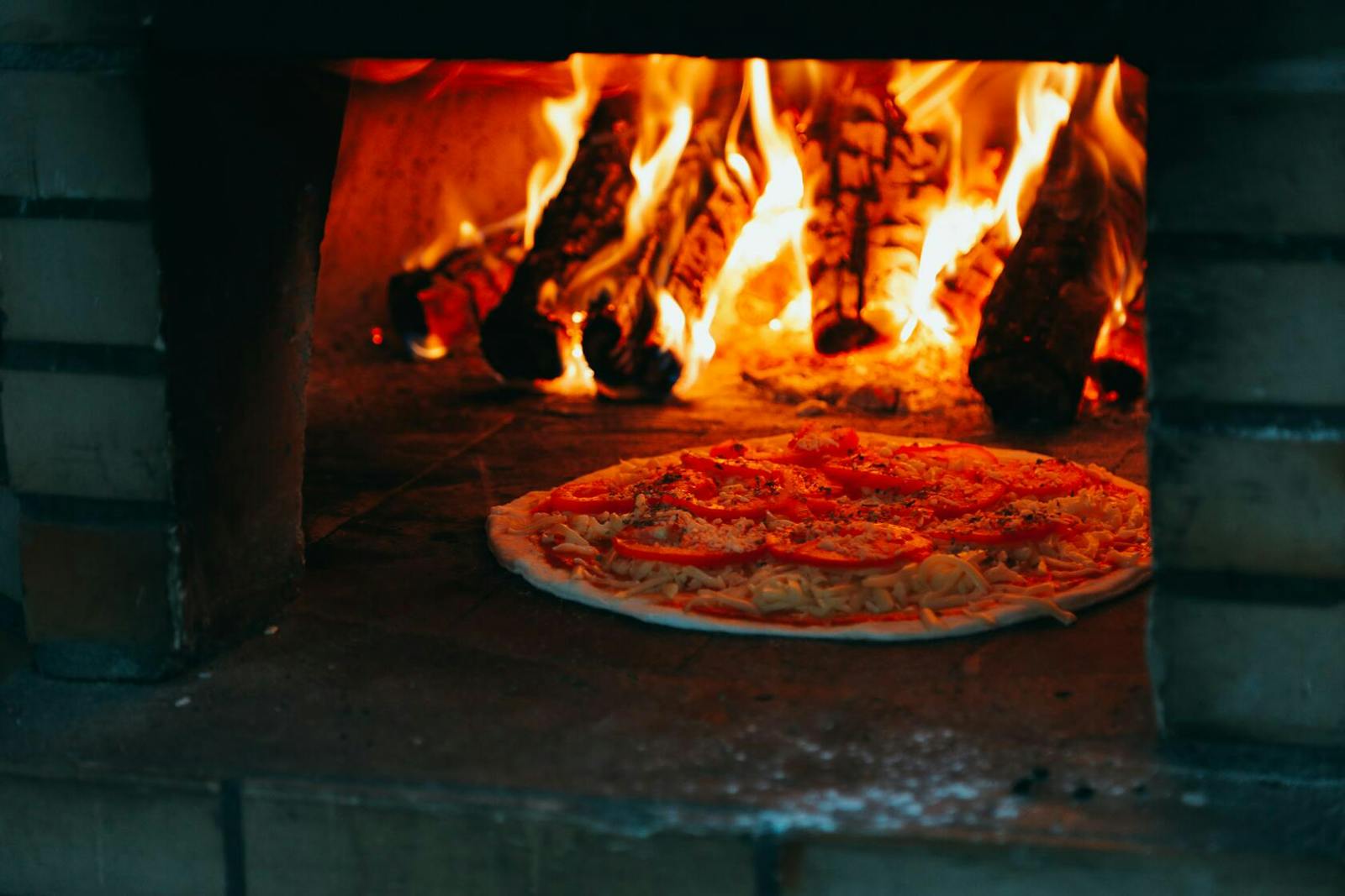 Image of a pizza cooking in a classic, masonry oven