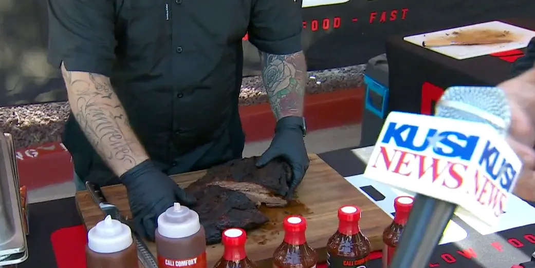Image of Cali BBQ employee preparing ribs while being interviewed by a news caster