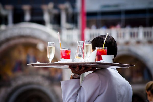 Image of a restaurant staff holding a tray of beverages