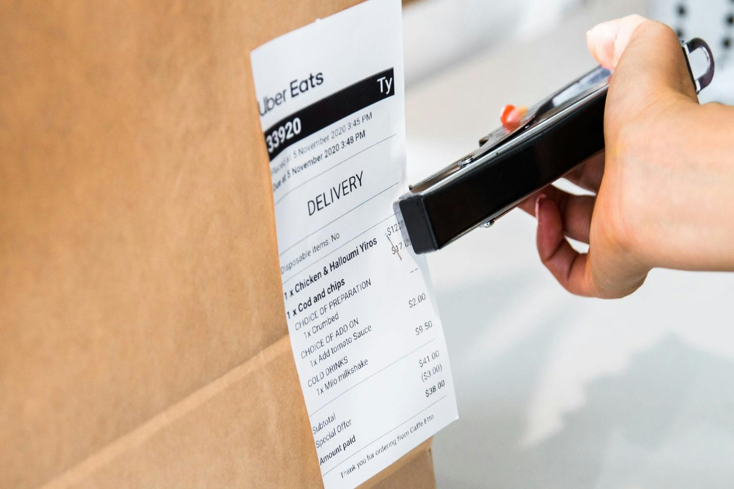 Image of a Uber Eats delivery receipt being stapled onto a food delivery package