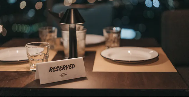 Image of a "reserved" tag sitting on top of a table at a restaurant