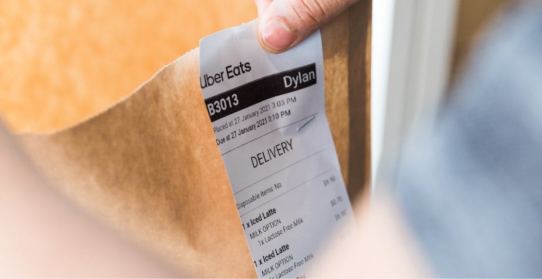 Image of a food delivery bag with an Uber Eats order receipt attached