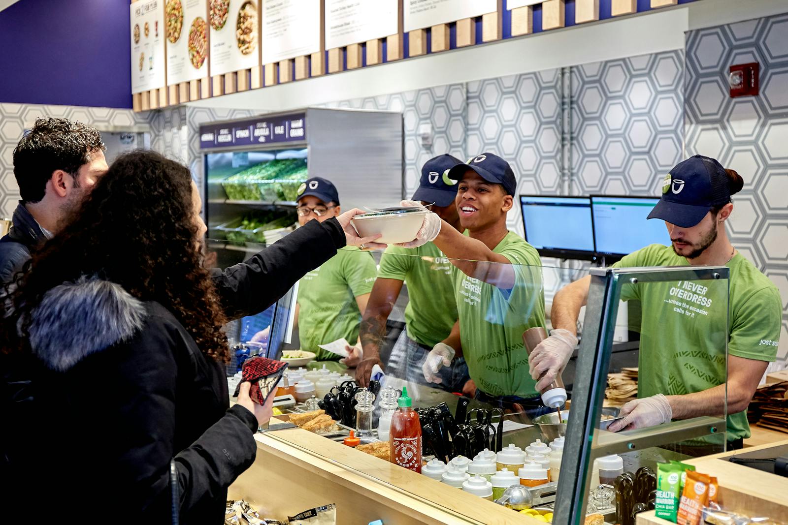 Image of Just Salad employees preparing orders for guests on the line