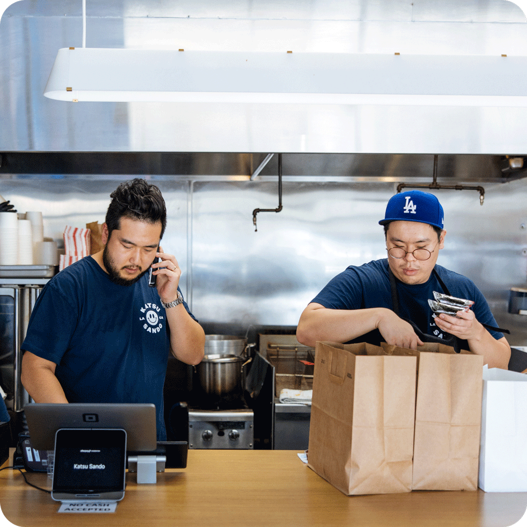 People using POS and packing food items in kitchen