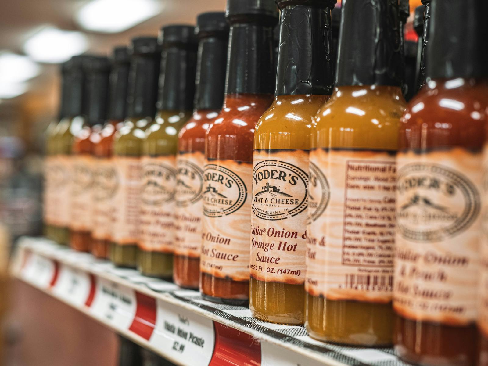 Some condiment bottles on a shelf. 