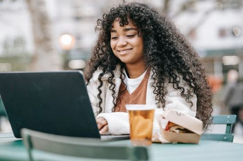 Image of a young lady hanging out at a café working on her laptop
