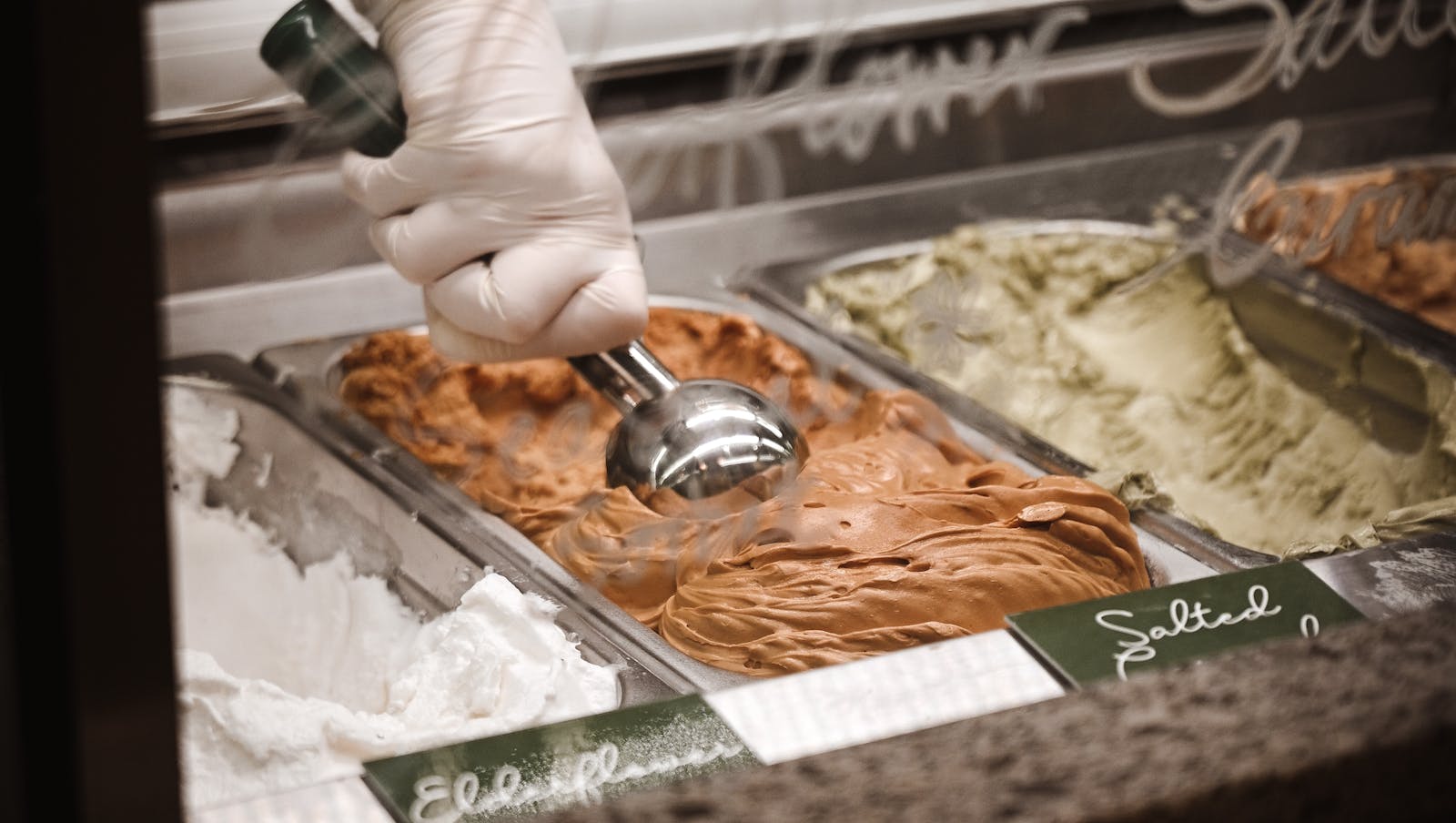 Ice cream being scooped in an ice cream parlor. 