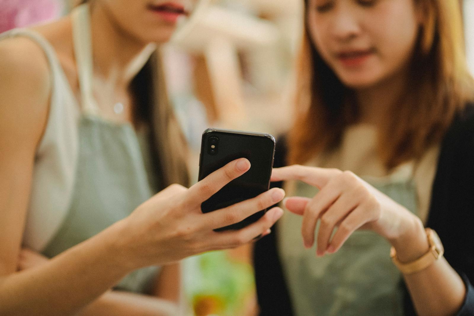 Image of two restaurant employees looking at an iPhone