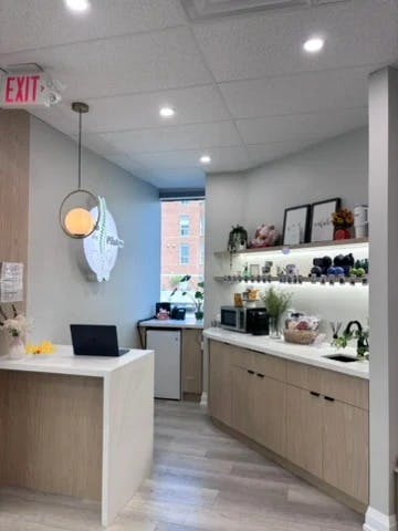 Bright, clean reception area with white walls, natural light, and minimalist décor creating a fresh and welcoming Pilates studio atmosphere.