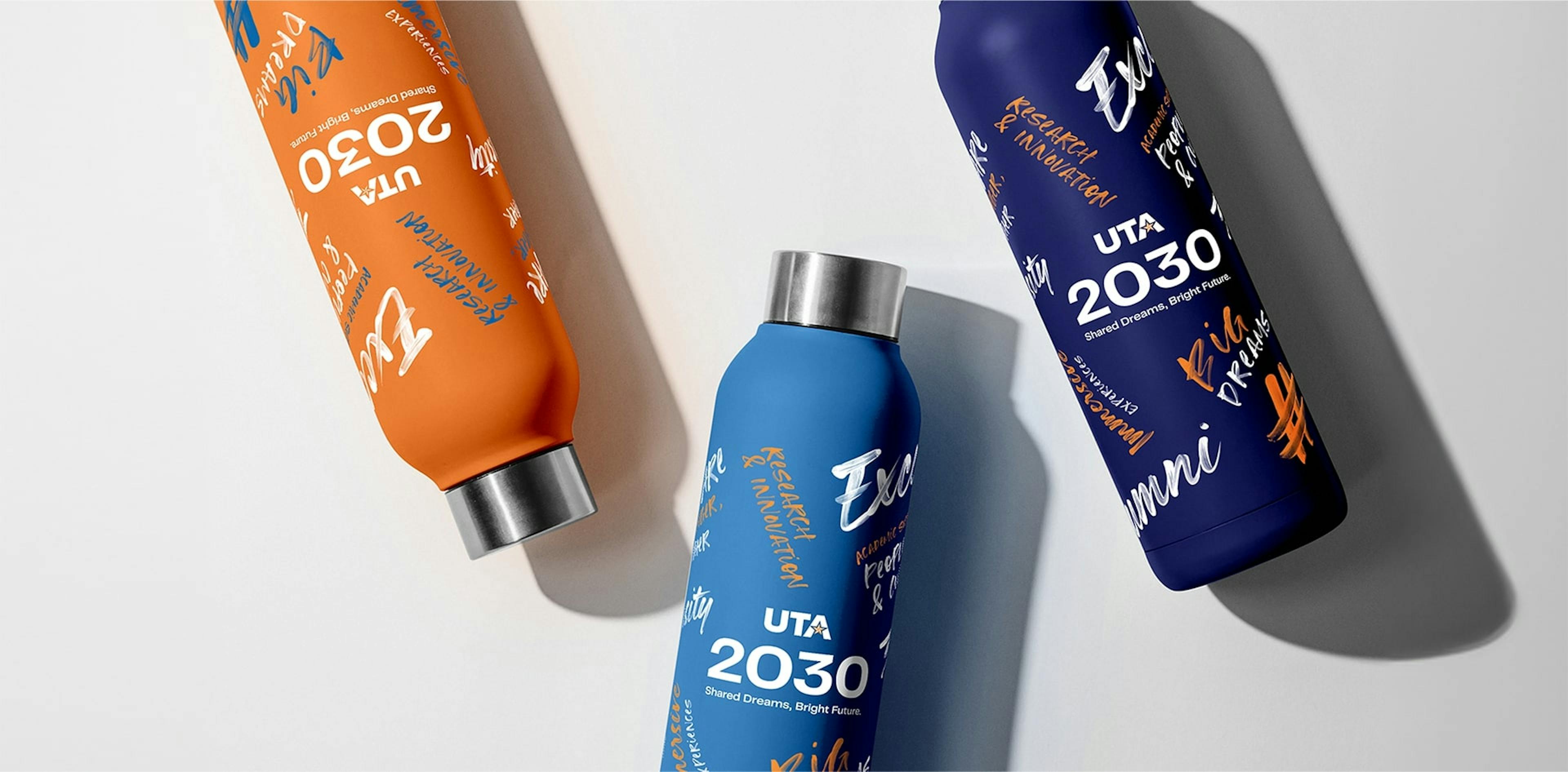 Three water bottles with hand-written style inscriptions, in blue, orange, and dark blue, featuring the text "UTA 2030" against a white background.