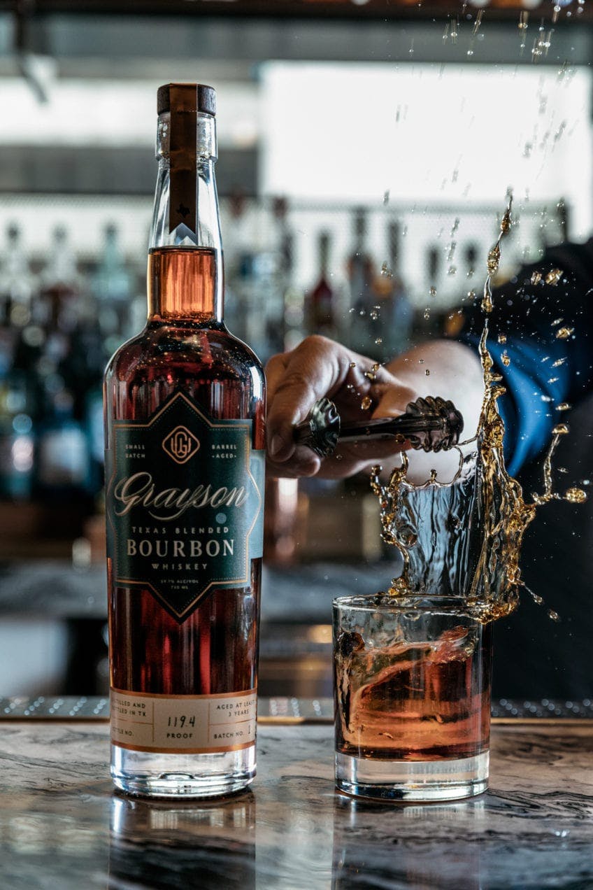 Artistic image of ice dropping into a glass of Grayson Bourbon