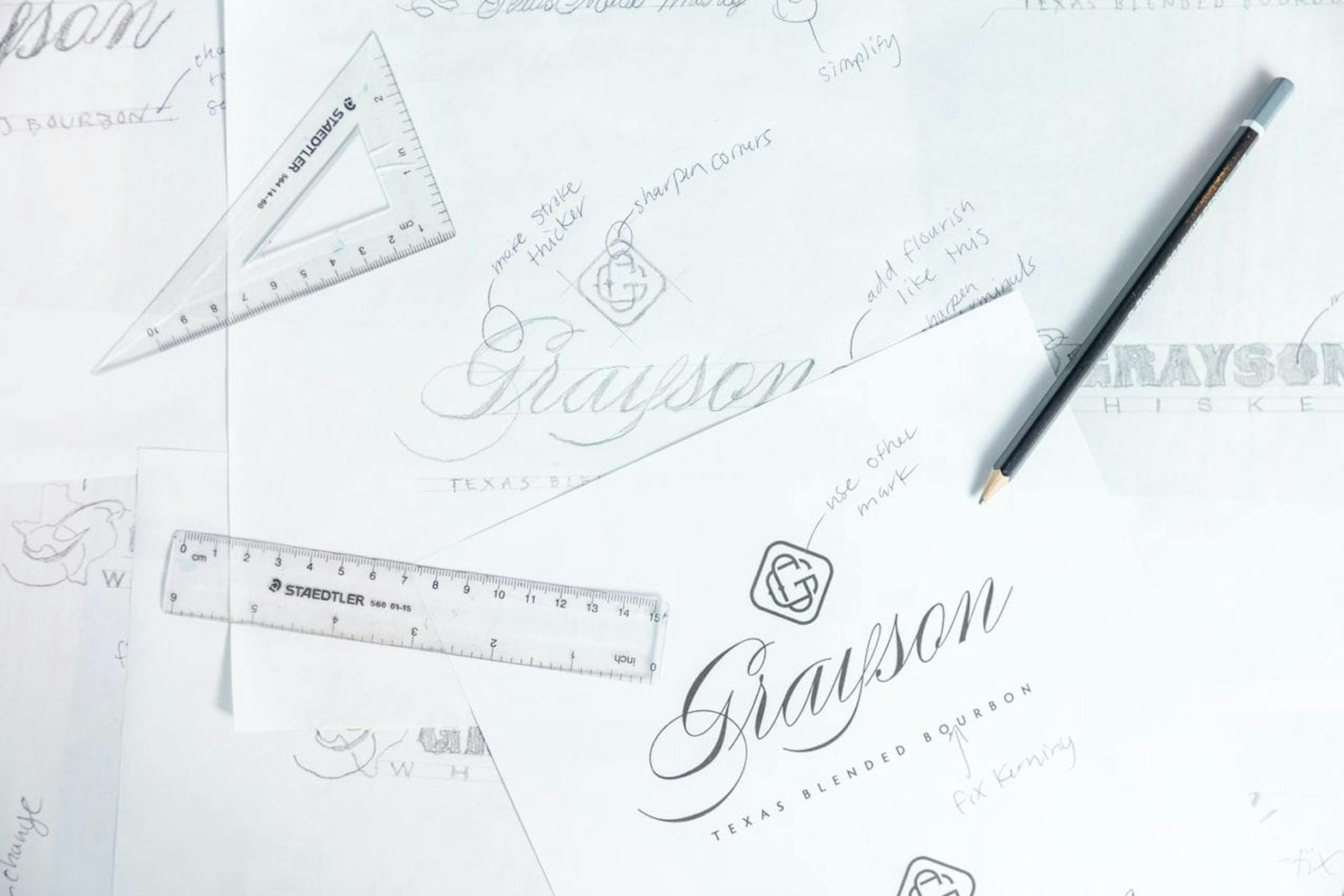 Grayson Bourbon Logo sketched out with pencil on a bunch of white pieces of paper