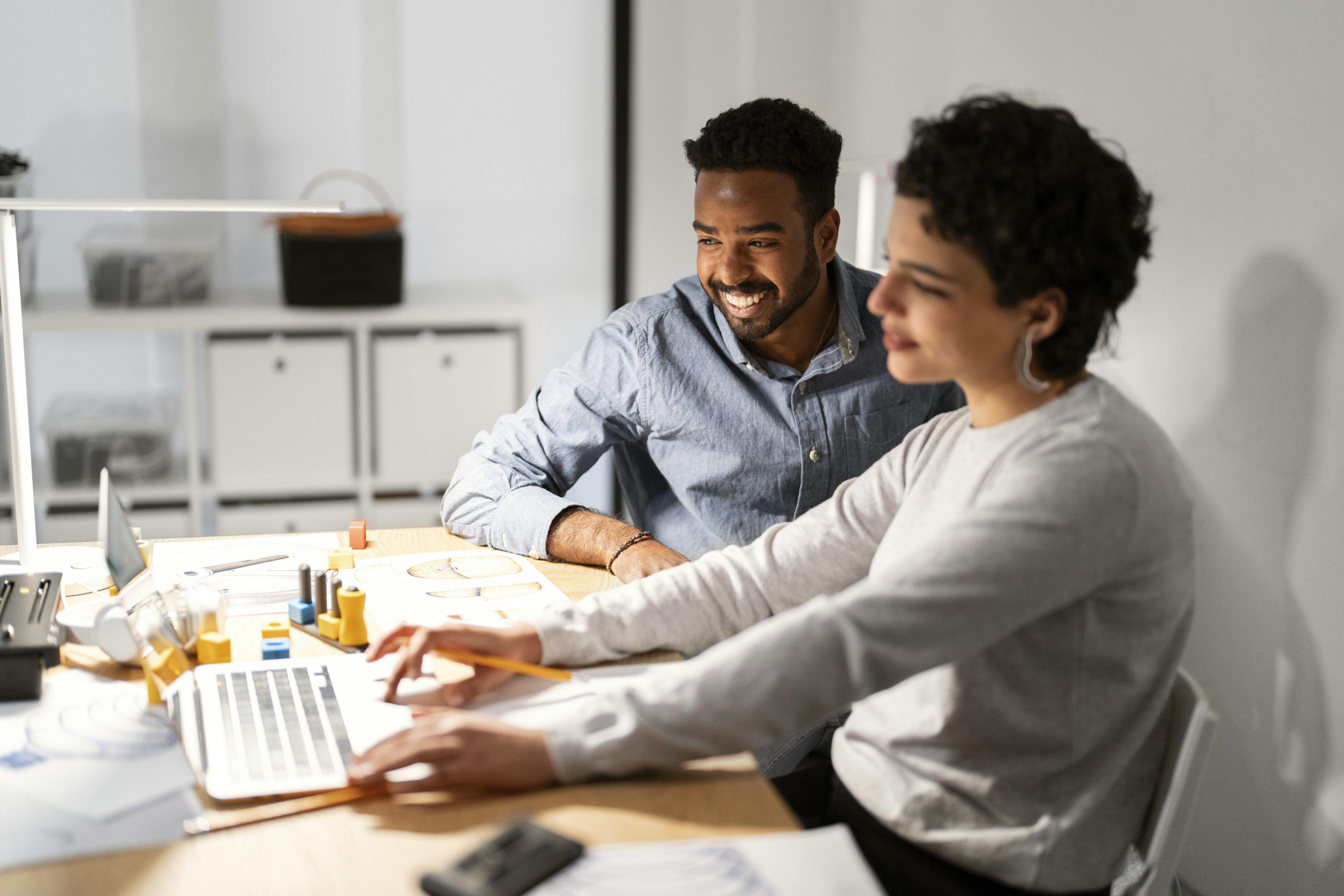 Two designers sitting in front of a computer working on a 3D model