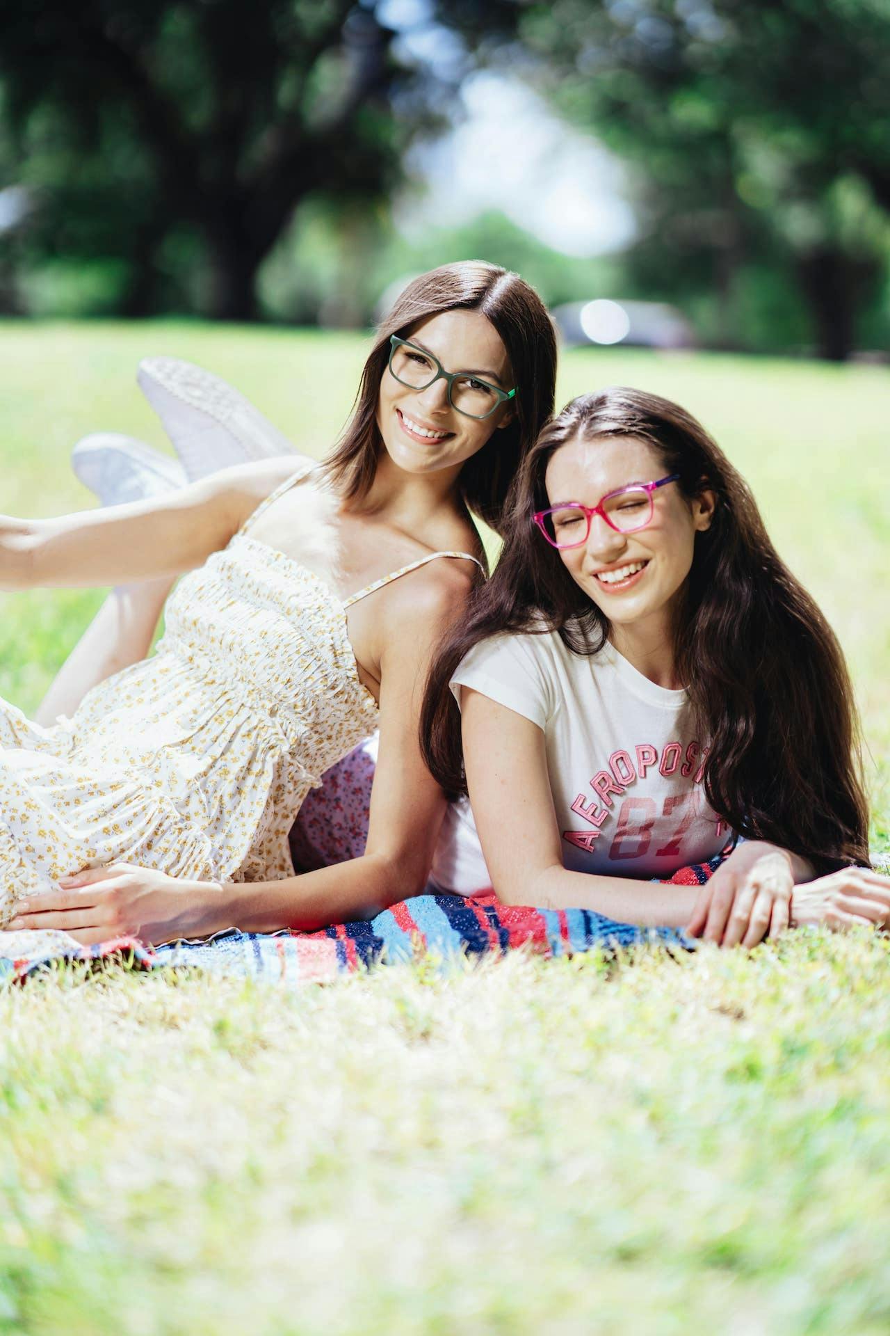 Two girls wearing Aéropostale eyewear laugh and talk in a local park