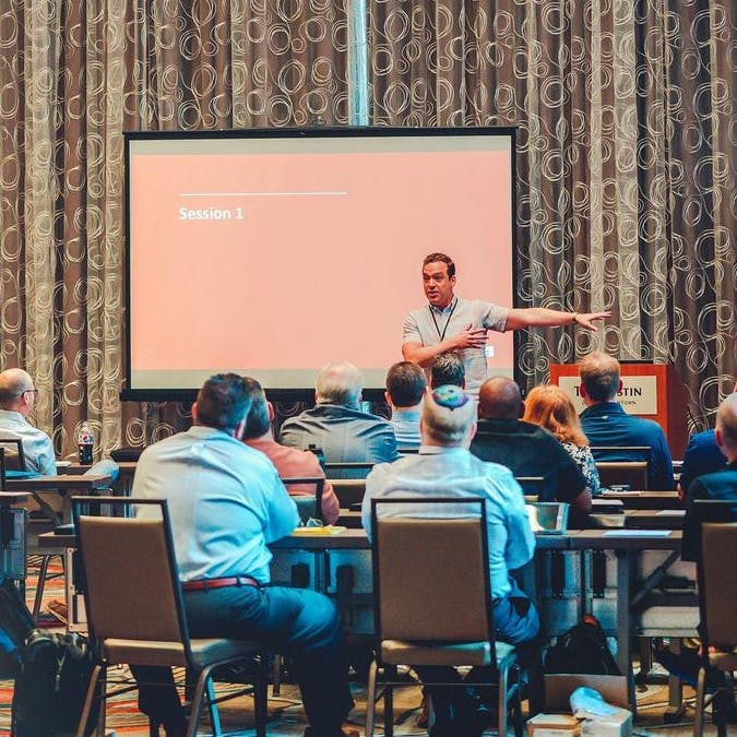 A group of people in a conference room listening to a male speaker as he talks about brand strategy workshops