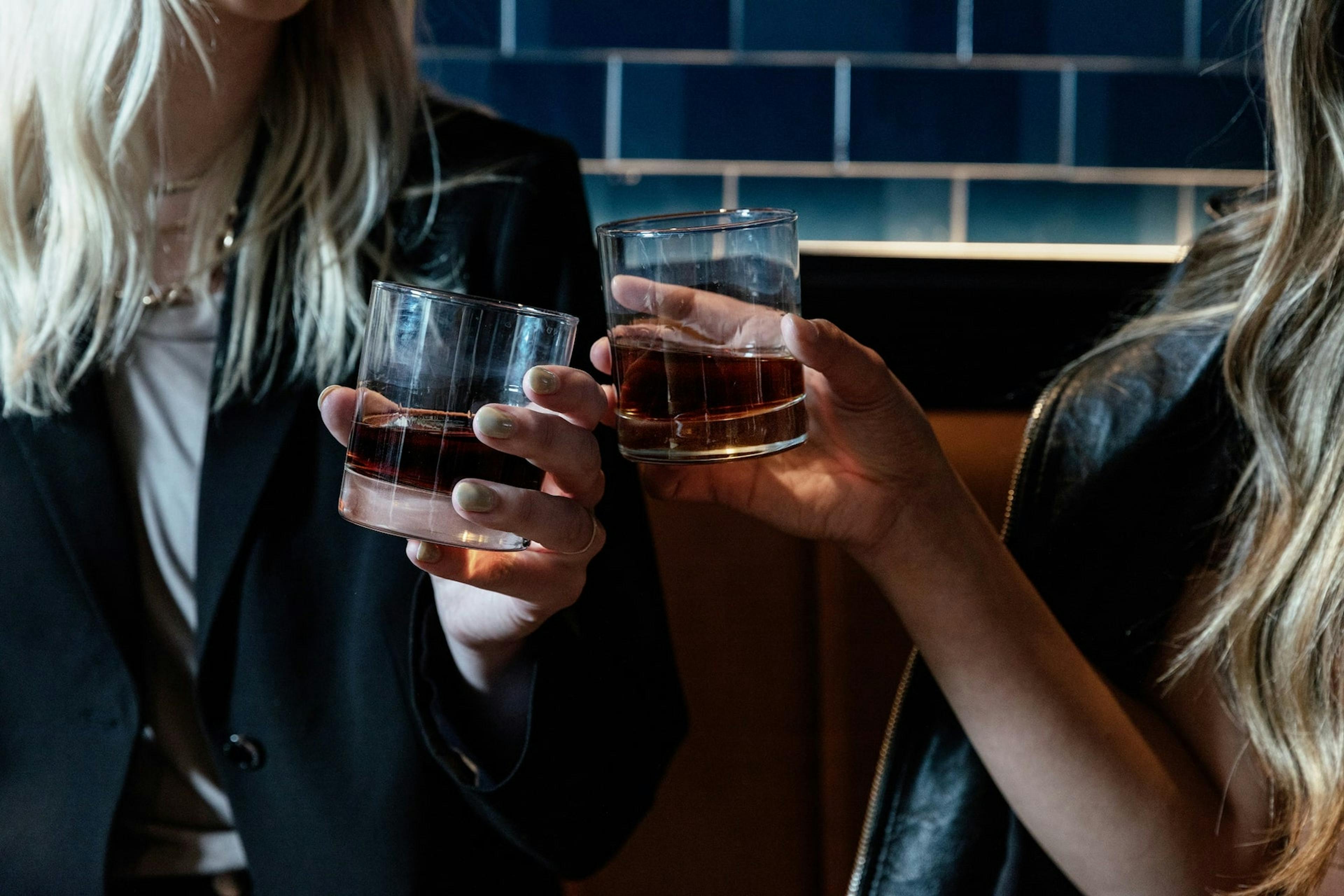 Two women clinking glasses of Grayson Whiskey